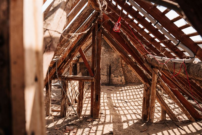 Exposed wooden roof rafters and beams inside an unfinished attic space