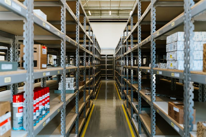 A narrow aisle between tall metal storage shelves in a warehouse
